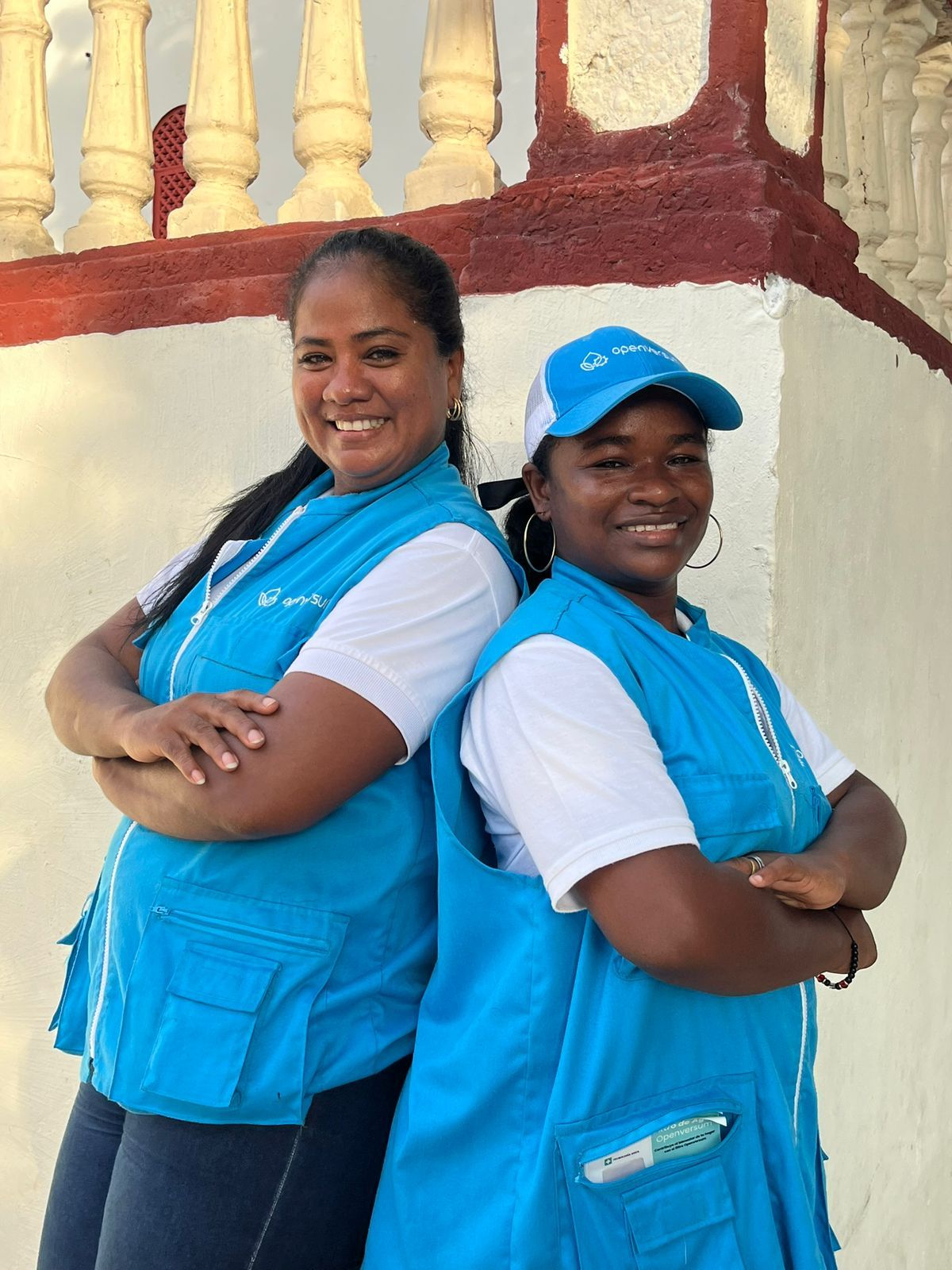 Two community outreach workers in blue vests smiling